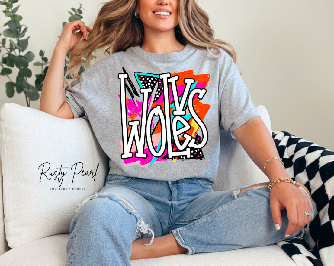 Woman wearing a gray t-shirt with colorful 'Wolves' design, sitting on a couch.