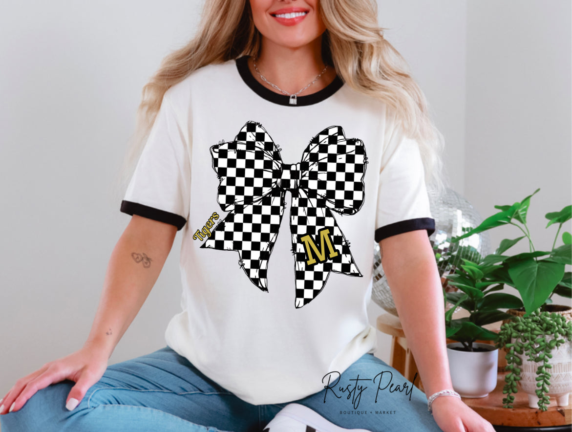 Woman wearing a white t-shirt with a black and white checkered bow design and 'Rusty Pearl' branding.