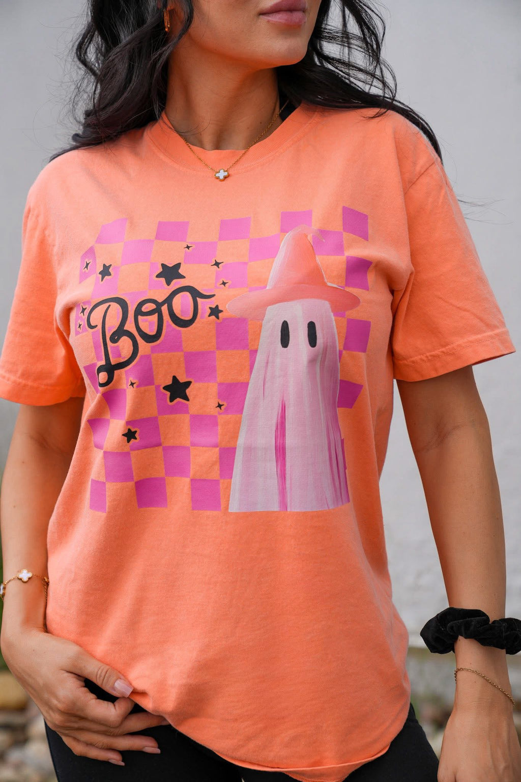 Person wearing an orange t-shirt with a ghost and 'Boo' design.