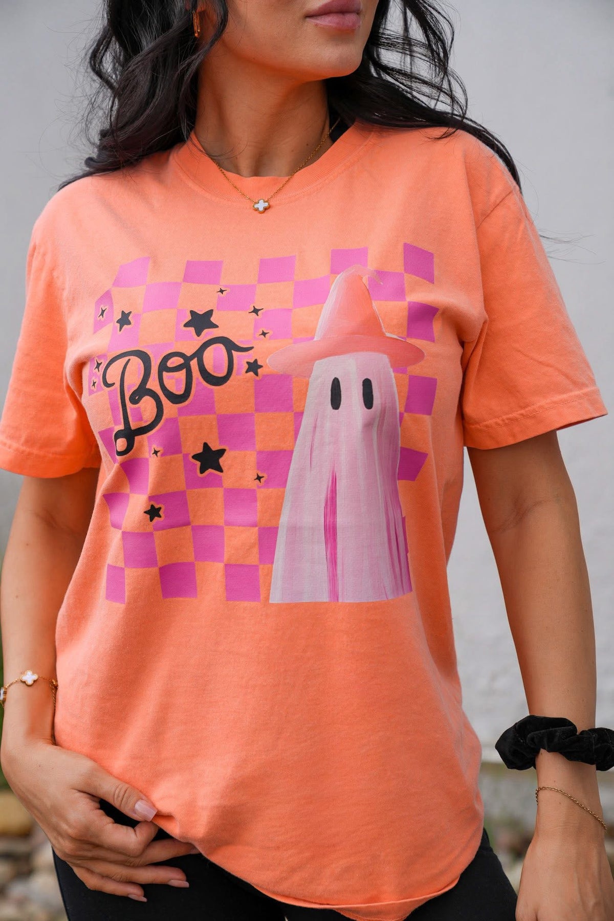 Person wearing an orange t-shirt with a ghost and 'Boo' design.