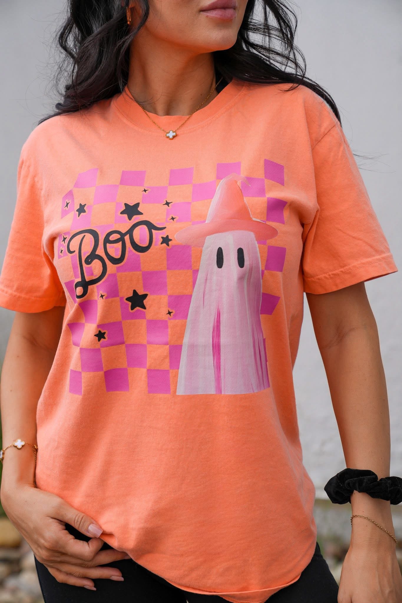 Person wearing an orange t-shirt with a ghost and 'Boo' design.