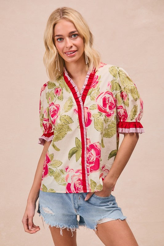 Woman wearing a floral blouse with red accents on a beige background